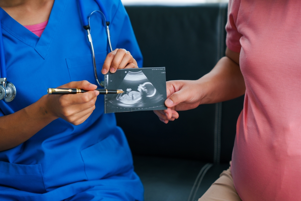 asian,female,doctor,and,nurse,consult,with,a,pregnant,woman